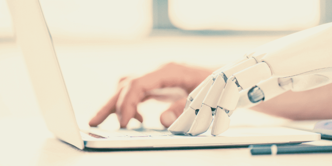 Mano humana y mano robot escribiendo juntas en un teclado, representando la convivencia entre inteligencia artificial y trabajo humano